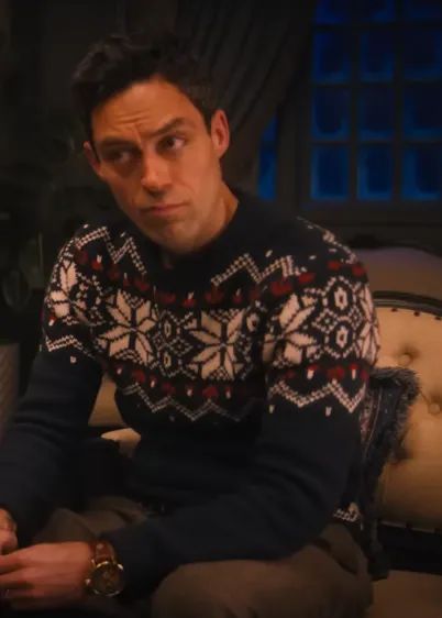 A person sitting inside, dressed in a holiday sweater with snowflakes, gazing off into the distance