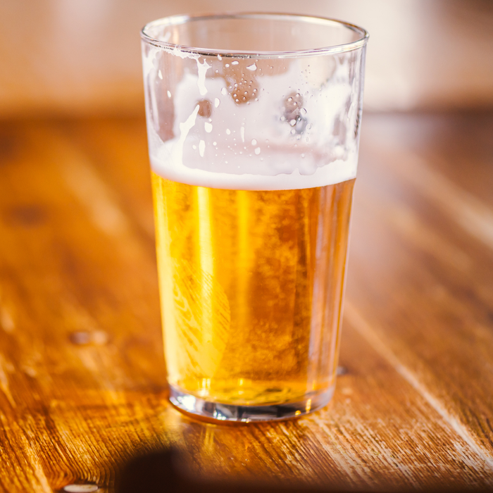 A glass of apple cider placed on a wooden surface in a traditional English pub