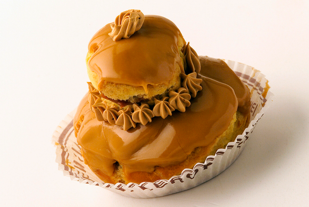 A delicious cream puff dessert with a glossy caramel topping, served in a decorative paper cup
