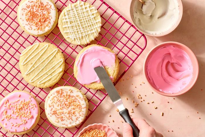 A person decorating cookies with pink royal icing