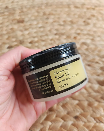 A reviewer showing off a tin of moisturizer.