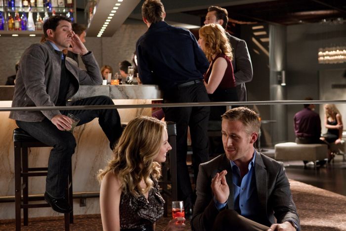 A group of friends enjoying drinks and conversation in a chic indoor bar. A man and woman are seated in the foreground, exchanging happy words