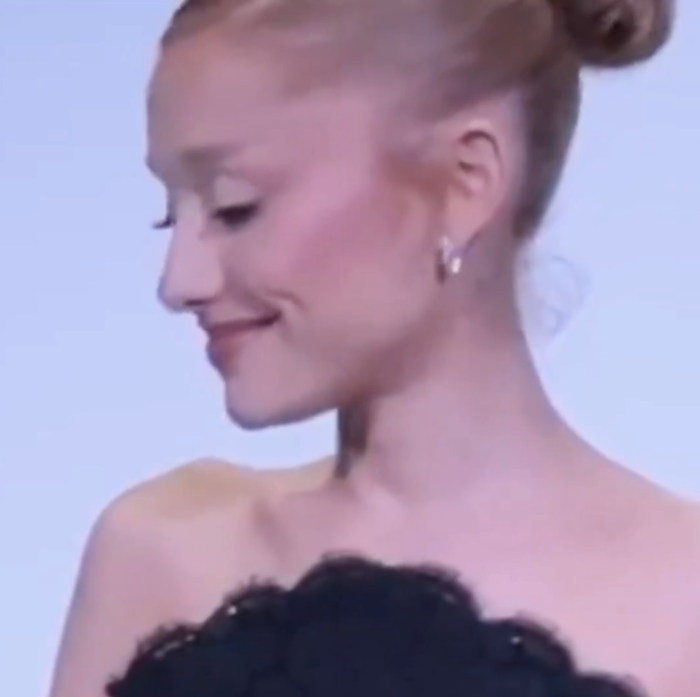 Ariana Grande in a sophisticated off-the-shoulder dress, her hair styled in a bun.