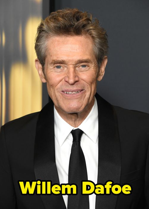 A man in a black suit and white shirt, beaming with a smile at a formal event
