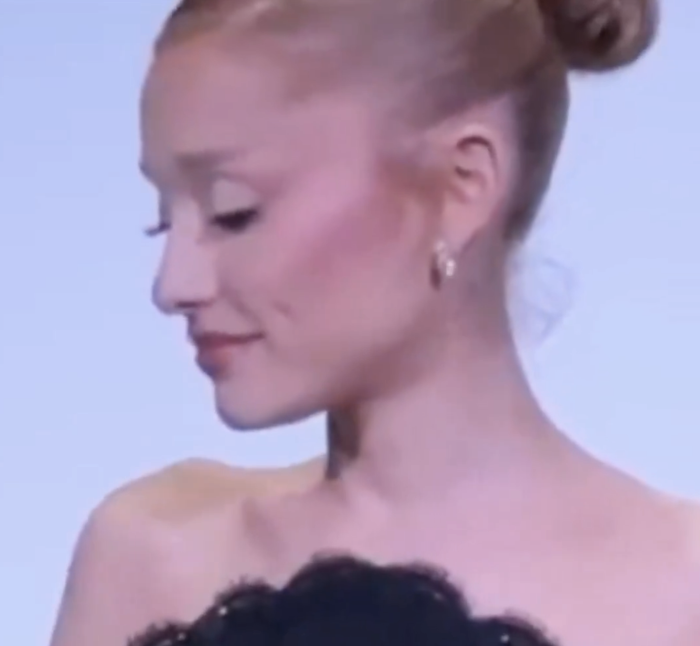 Ariana Grande, her hair in a bun, dons a strapless textured dress as she looks off to the side.