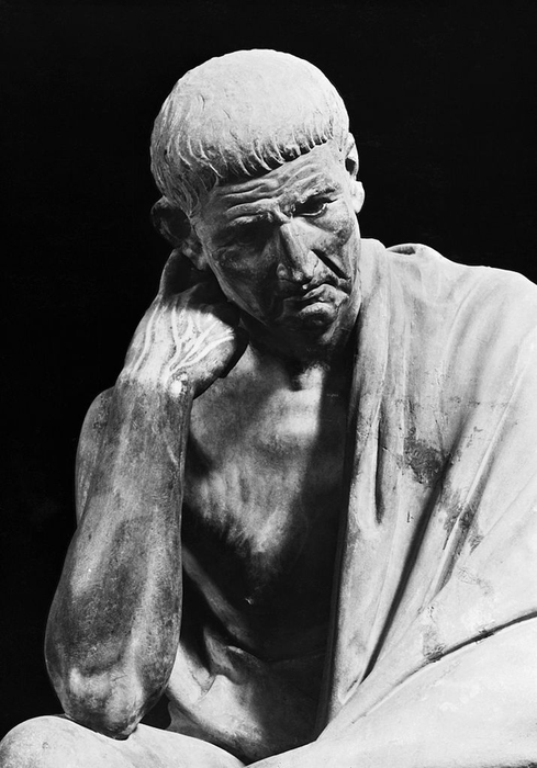 A timeless sculpture showing a pensive man draped in a cloak, with his head resting on his hand in deep thought