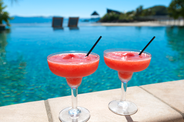 Two refreshing cocktails placed by a resort poolside, with the beach visible in the background.