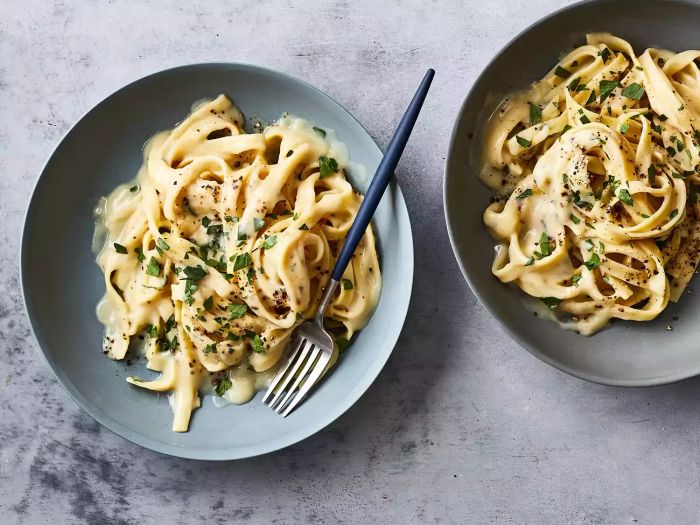 Fettuccine with Vegan Cauliflower Alfredo Sauce, Served in Two Bowls with a Fork for Eating