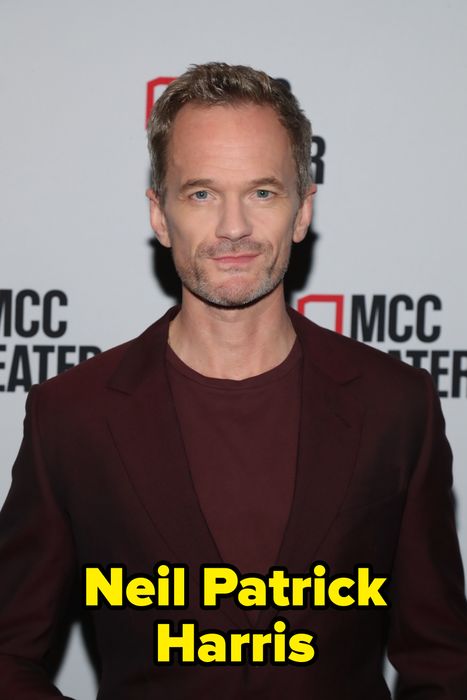 A person attending an MCC Theater event in a dark suit jacket and shirt, posing for a photo in front of a branded backdrop