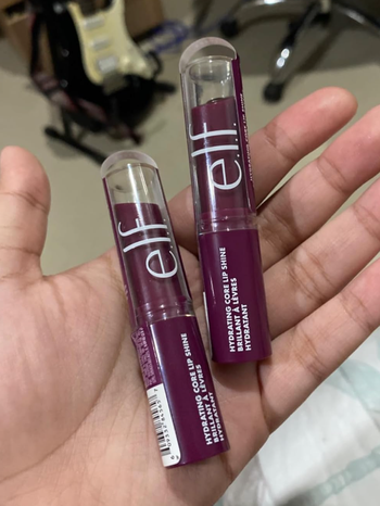 Hand holding two tubes of E.l.f. Hydrating Core Lip Shine lip balms
