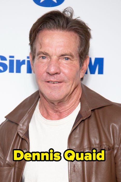 A person in a white shirt and brown leather jacket stands in front of a media event backdrop