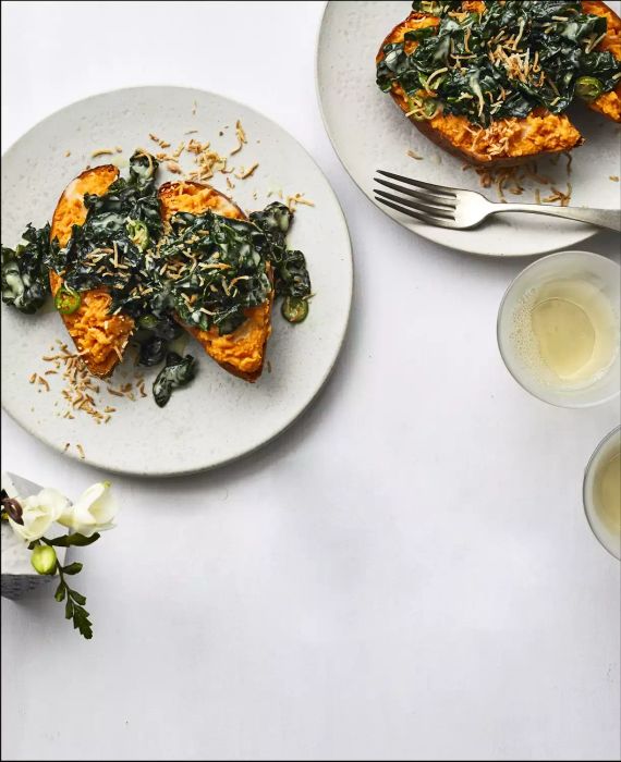 Two Loaded Sweet Potatoes with Coconut and Kale Served on Individual Plates with a Fork for Eating