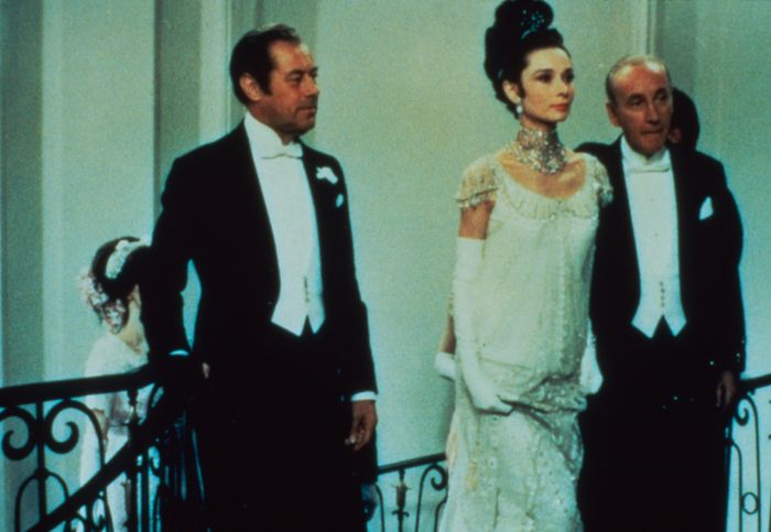 An elegant gathering with guests dressed in formal evening wear, showcasing a woman in a beautiful beaded gown and a bold statement necklace
