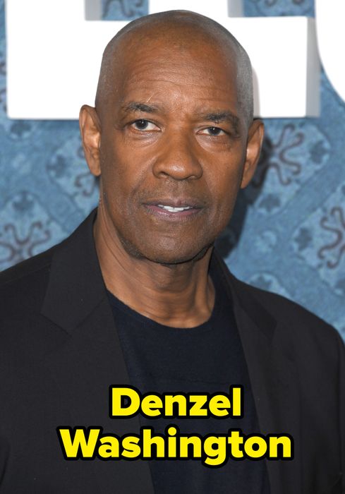 Someone in a black jacket and dark shirt attending an event, standing in front of a patterned backdrop