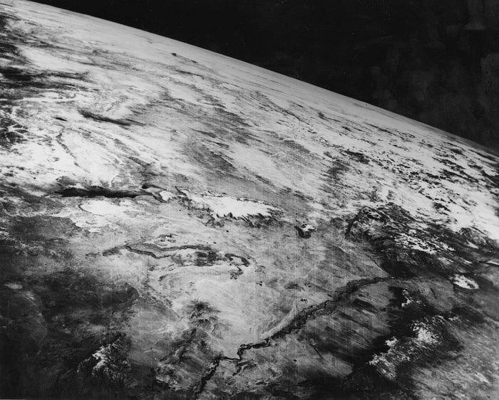A historic photograph of Earth's surface taken from space, showcasing expansive landscapes and cloud patterns.
