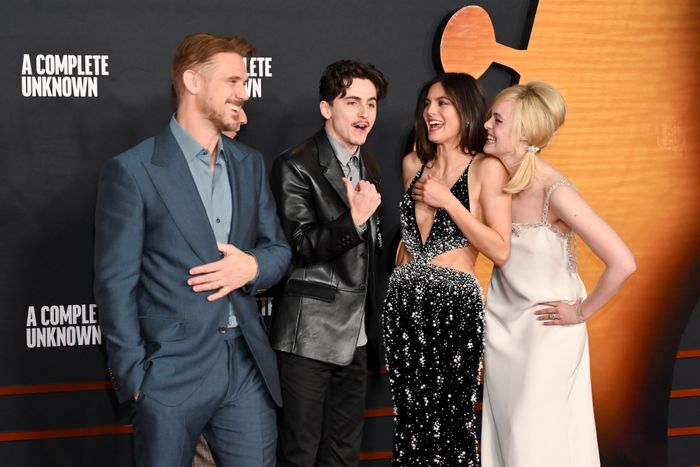 A group of actors in formal attire laughing and posing at a movie premiere event.