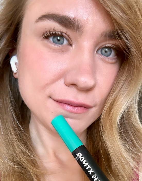 Close-up of a reviewer holding a mascara tube with fully applied lashes