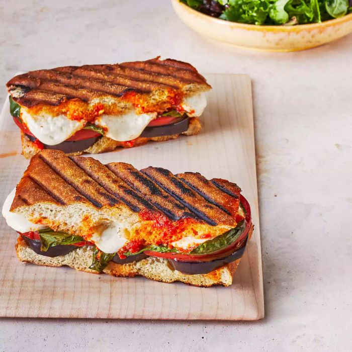 Two eggplant parmesan paninis rest on a cutting board.