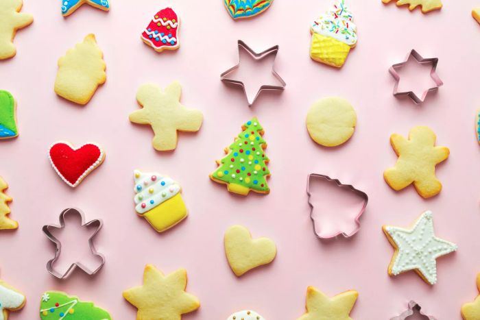A display of decorated and plain sugar cookies alongside a variety of cookie cutters on a table