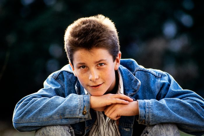 A teenager in a denim jacket, striking a contemplative pose outdoors