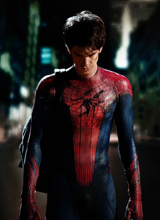 Andrew, dressed as Spider-Man with a backpack, stands in a dimly lit city street, gazing down.