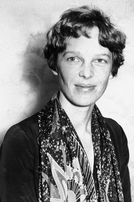 A vintage black-and-white photo of a woman with short hair, dressed in a jacket and patterned scarf