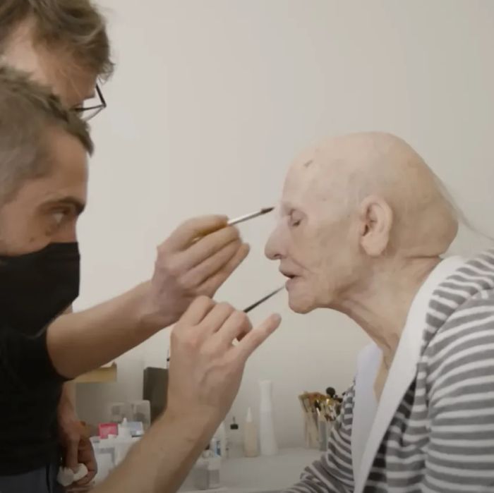 Makeup artists carefully apply prosthetics to Demi's face, crafting an aged look for a film or TV production.