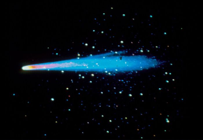 A radiant comet with a shimmering tail moves across a starry sky, leaving a luminous trail behind.