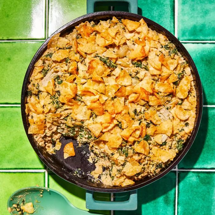Spinach and Artichoke Quinoa Casserole Served in a Skillet With a Blue Spoon for Serving