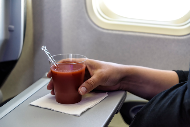 A glass of tomato juice placed on a table near the window of an airplane