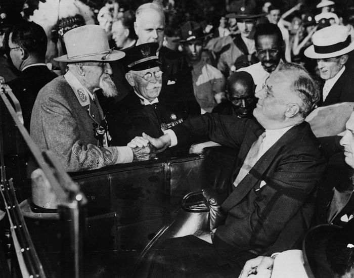 Two senior men shaking hands in a car at a significant historical event.