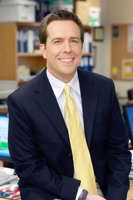 A person in a professional office environment, dressed in a suit and patterned tie, smiling warmly at the camera.