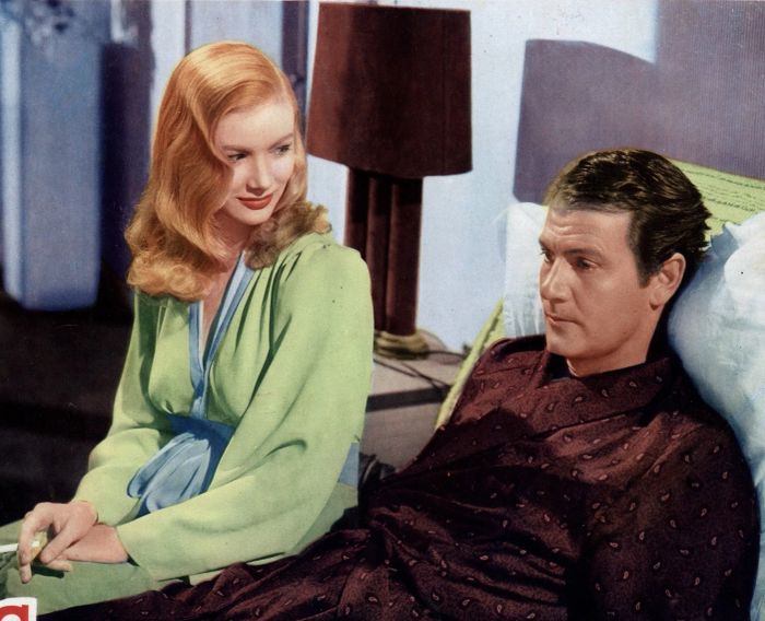 Joel McCrea and Veronica Lake sitting and conversing on a bed