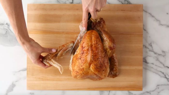 Hands removing a turkey wing using a knife