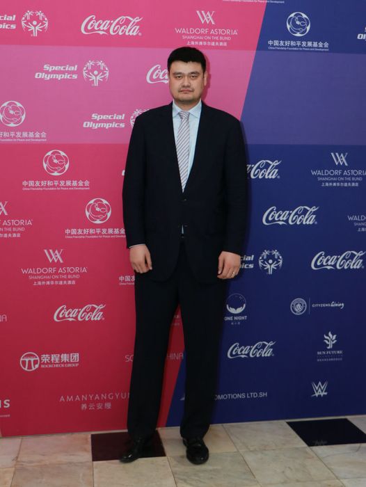 Yao, dressed in a sharp suit, appears on the red carpet at a Special Olympics event, with sponsor logos in the background.