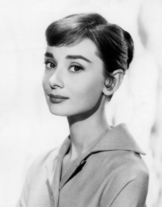 Audrey Hepburn exudes timeless elegance with an updo and a tailored collar, embodying grace and poise.