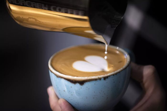 pouring creamer into coffee