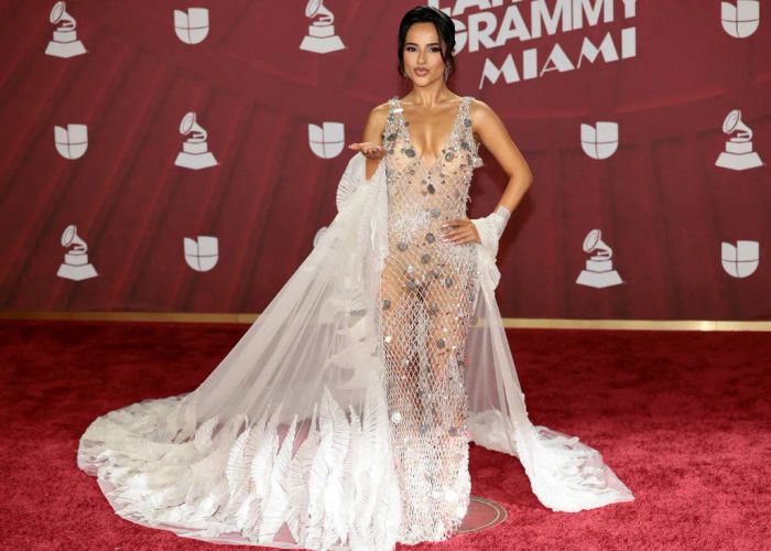 Becky struts down the red carpet in a sheer, embellished gown with a flowing train, posing as she blows a kiss.