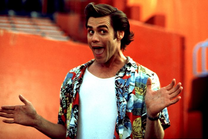 A person poses with an animated expression, dressed in a tropical shirt layered over a white undershirt, bringing a playful vibe to the moment.