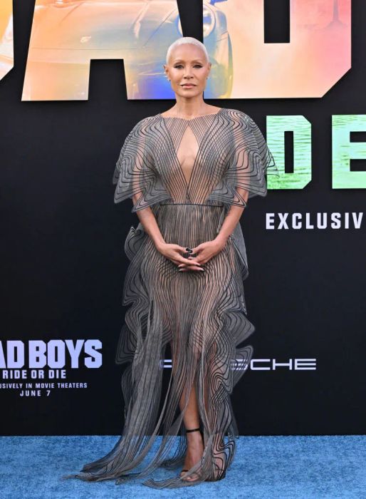 Jada graces the red carpet in a transparent, geometric-patterned dress, complete with structured wings on her shoulders.