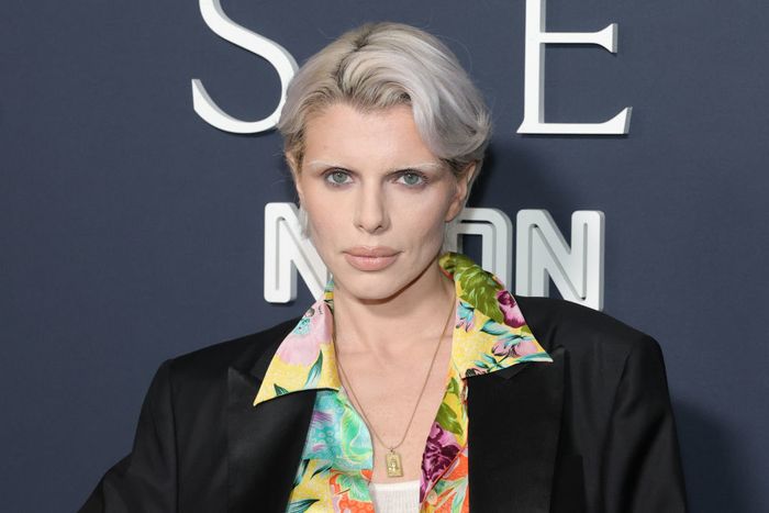 A person with short hair is spotted at a public event, sporting a floral shirt and a sharp blazer, exuding effortless style.