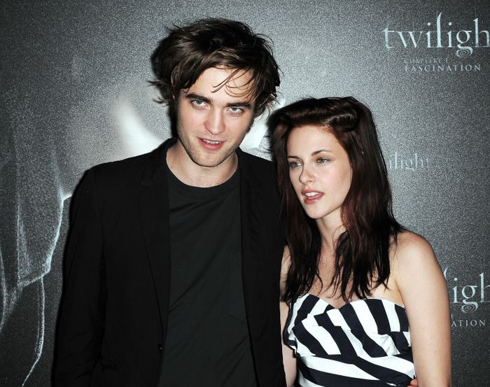 At a 'Twilight' event, two individuals strike a pose. One dons a dark suit, while the other wears a strapless dress with a bold geometric pattern.