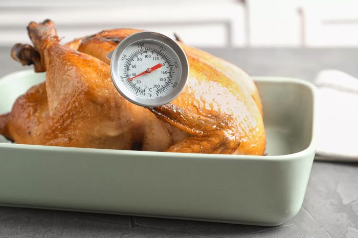 A roasted turkey with a meat thermometer placed in a baking dish on the table