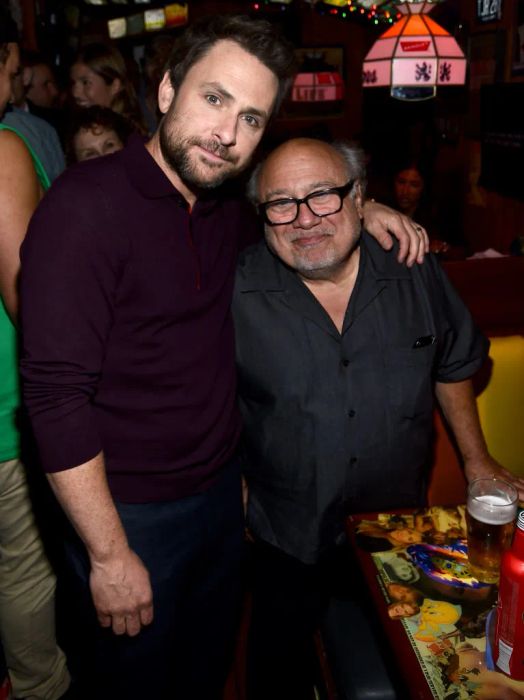 Charlie and Danny, both dressed casually, pose together. Danny reaches up to Charlie's shoulder.