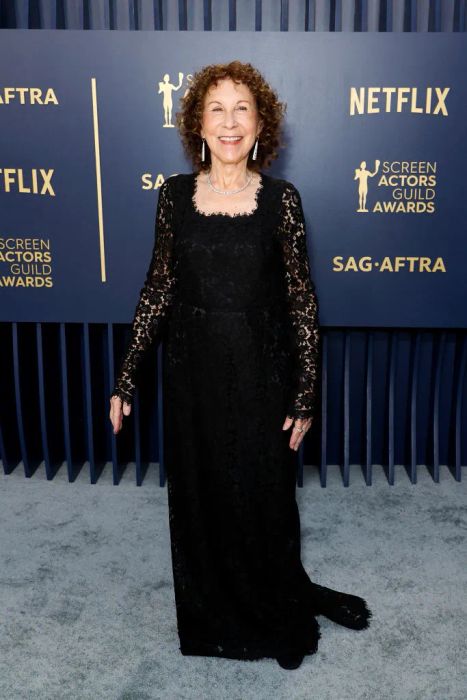 Rhea stuns in an elegant lace gown at a Screen Actors Guild Awards event, set against a glamorous backdrop.
