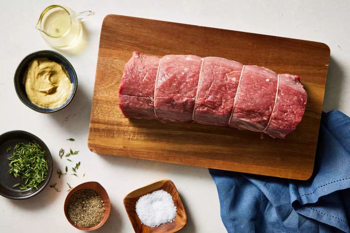 A raw beef filet placed on a cutting board alongside various ingredients