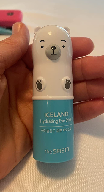 reviewer holding the blue hydrating stick, topped with a cute polar bear-shaped cap