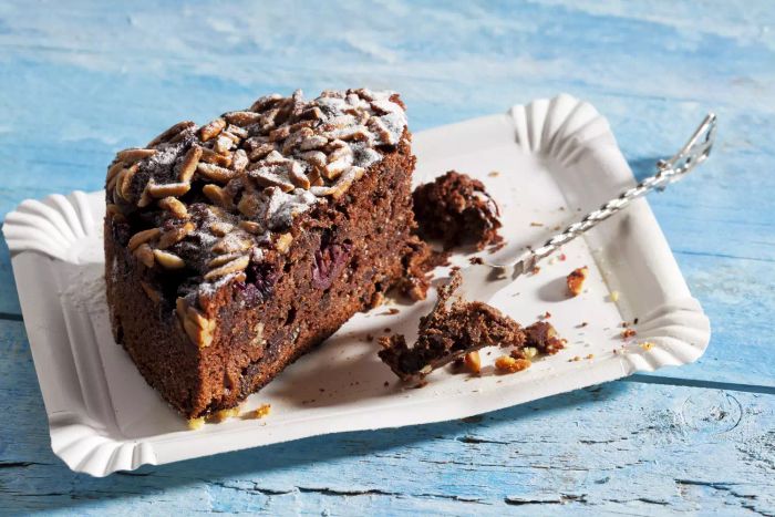 A chocolate almond cake with a pastry fork resting on a paper plate