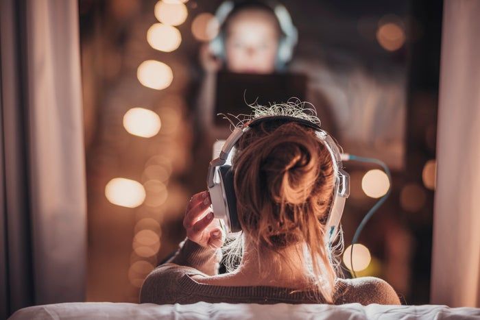 A woman wearing headphones, gazing out the window.