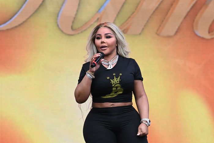 Lil' Kim takes the stage in a black t-shirt adorned with a gold crown graphic, paired with black pants